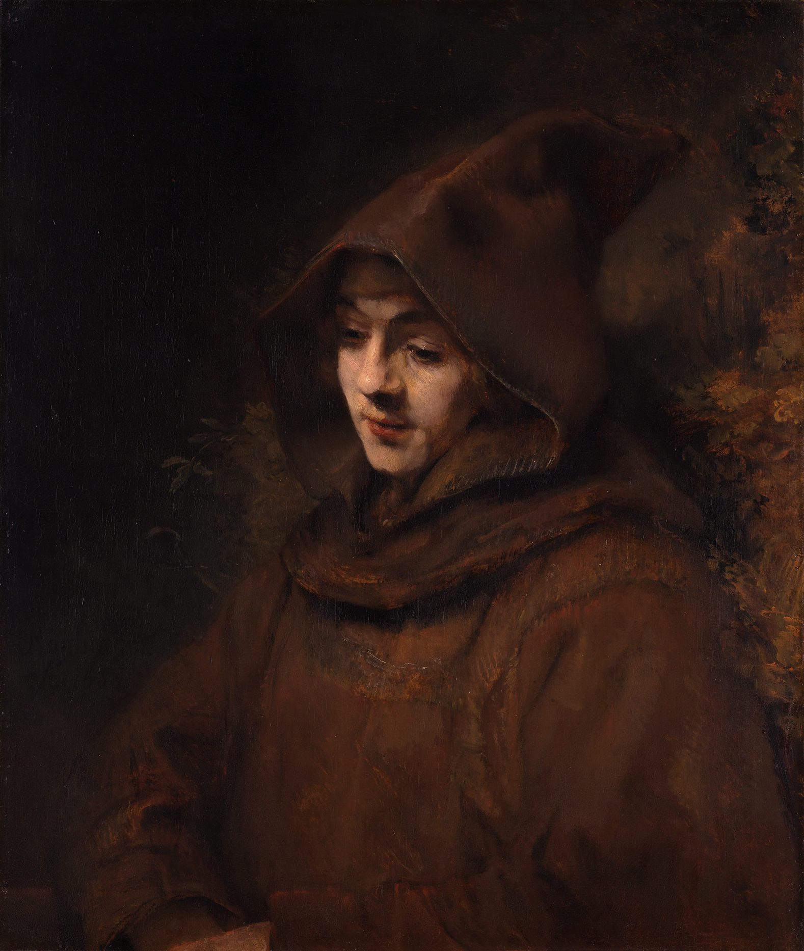 Baroque oil painting by Rembrandt showing his son Titus wearing a dark brown hooded monk's robe, with his face softly illuminated from the side.
